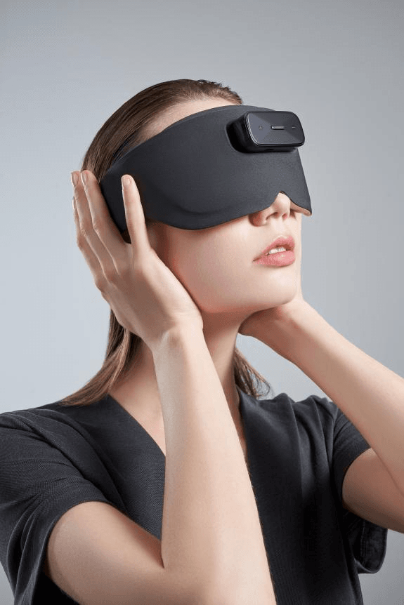A woman wears the BrainCo Easleep BCI sleep device, a comfortable eye mask, preparing for restful sleep.