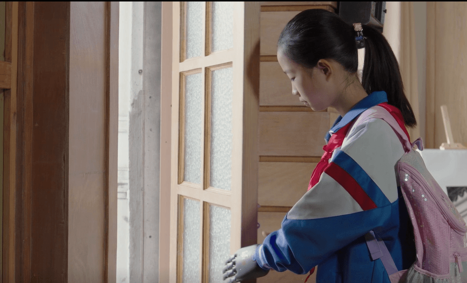 一位穿着校服的女孩正在使用BrainCo仿生手开门